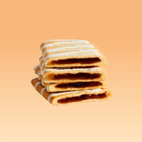 Stack of four s'mores pastries with chocolate filling and white icing drizzle on peach background.