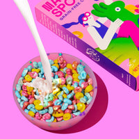 Pink bowl filled with colorful fruity cereal in blue, yellow, and red pieces with white spoon and Magic Spoon box.