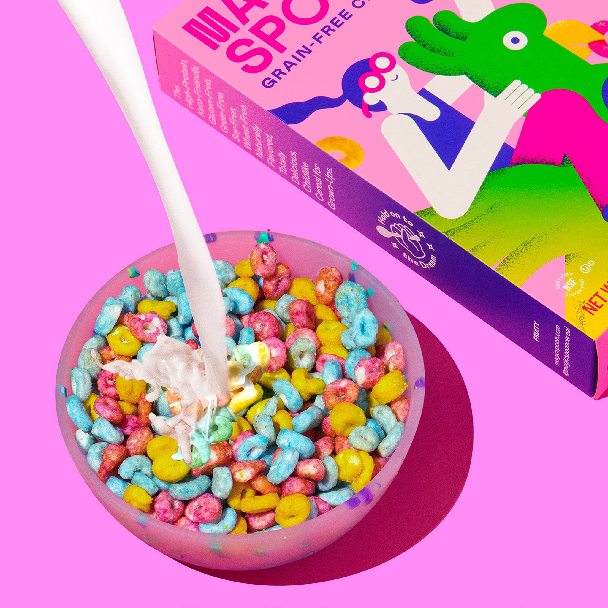 Pink bowl filled with colorful fruity cereal in blue, yellow, and red pieces with white spoon and Magic Spoon box.
