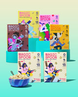 Six Magic Spoon cereal boxes in various flavors with a blue bowl filled with cereal on turquoise background.
