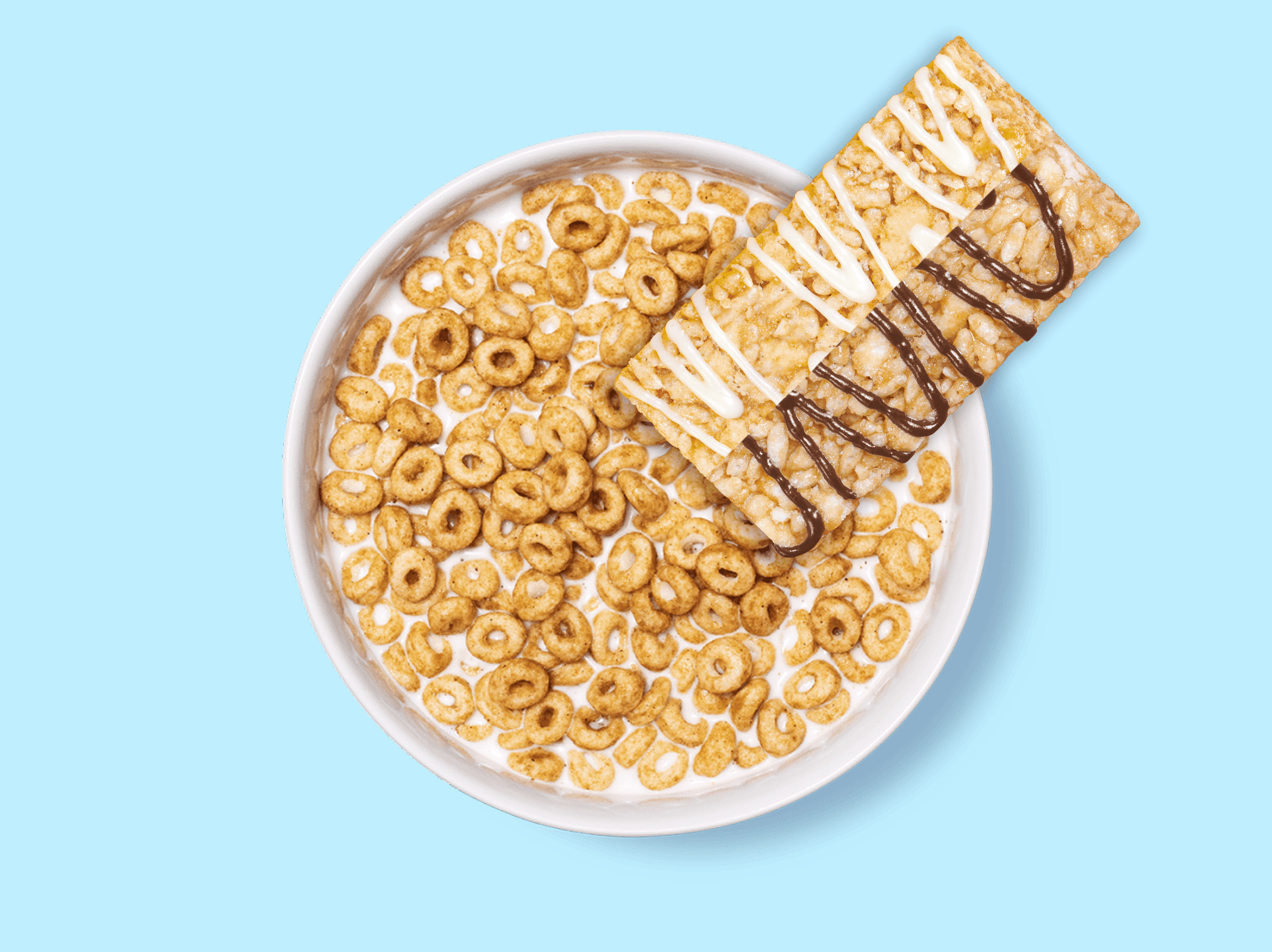 White bowl filled with golden cereal rings and chocolate-drizzled treat bars on light blue background.